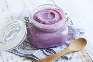 Creamy vibrant purple Ube Halaya in a glass jar with wooden spoon beside it, natural lighting