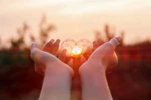 Hands holding a small heart-shaped object, surrounded by soft sunlight, representing thankfulness and appreciation in daily life