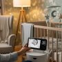 Happy parent checking sleeping baby on secure non-WiFi monitor screen in cozy nursery setting