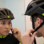 Person adjusting bike helmet side straps to form a V shape under the ears while looking in a mirror