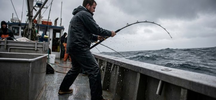 Angler wearing non-slip fishing shoes standing securely on a wet fiberglass boat deck.