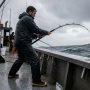 Angler wearing non-slip fishing shoes standing securely on a wet fiberglass boat deck.