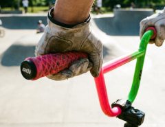 Rider hands holding patterned BMX grips on handlebars during a jump.