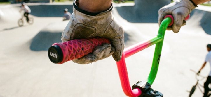 Rider hands holding patterned BMX grips on handlebars during a jump.