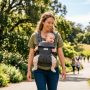 Smiling mother wearing an affordable ergonomic baby carrier while walking outdoors in California.