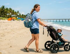Parent carrying a durable diaper backpack on a sunny Florida beach. (9 words)